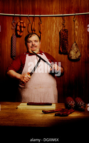 Fett Metzger Schärfen eines Filetieren Messers in einer Metzgerei mit einem hölzernen Ambiente Stockfoto