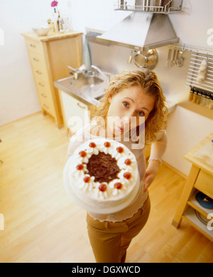 Frau in einer Küche hält eine Schwarzwälder Kirsch Torte Stockfoto
