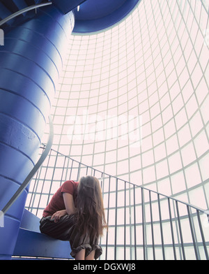 Frau mit langen Haaren sitzen auf den Stufen einer Treppe mit Glassteinen Stockfoto