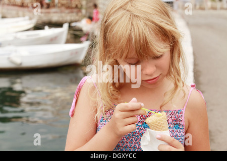 Lächelndes blondes Mädchen isst Eis. Outdoor-Sommer-Porträt Stockfoto