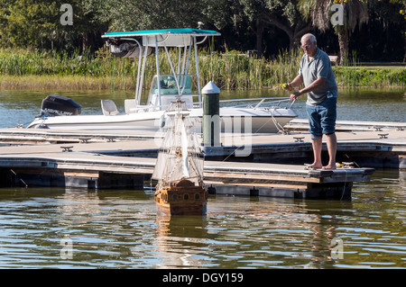 Älterer Mann startet eine Skala Modell spanische Galeone Segelschiff auf See Dora in Florida. Stockfoto