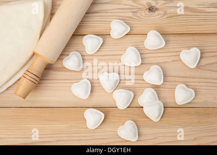 Knödel in einer Herz-Form-Teig und Nudelholz auf dem Holztisch. Stockfoto