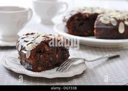 Schokoladen-Kuchen mit Mandeln auf Vintage Teller mit Tasse Tee Stockfoto