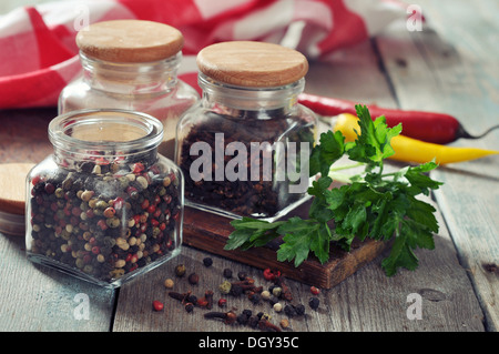 Gewürze in Glasflaschen mit Chili-Pfeffer auf hölzernen Hintergrund Stockfoto