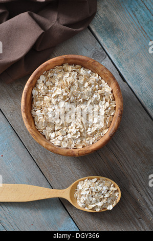 Haferflocken in Holzschale mit Löffel auf hölzernen Hintergrund Stockfoto