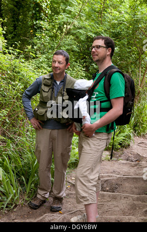 Vater und Sohn tragen sein kleines Mädchen in einer Schlinge, genießen Sie einen Spaziergang auf dem Lande Stockfoto