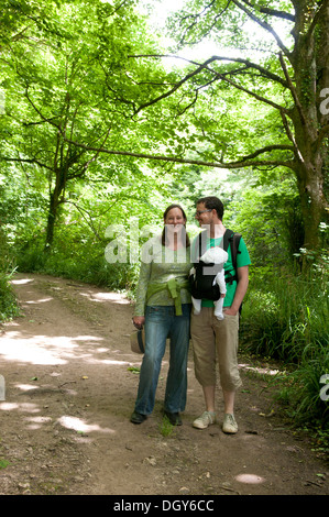 Paar mit ihrem Baby im Tragetuch genießen Sie einen Spaziergang auf dem Lande Stockfoto