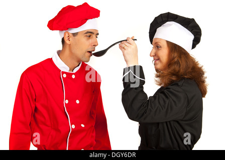 Frau Koch verleiht Geschmack Suppe vom Löffel zu seinen Kollegen Mann isoliert auf weißem Hintergrund Stockfoto