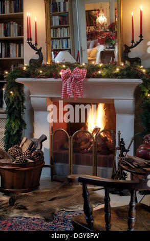 Brennen, offener Kamin mit Weihnachtsschmuck in einem stilvollen Lesesaal Stockfoto