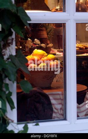 Blick von außen durch ein Fenster in eine Küche in ein vorweihnachtliches Stil dekoriert mit eine Schüssel mit Obst und Kuchen Stockfoto