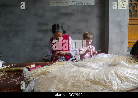 Begegnungen in China, europäische Mädchen helfen auf alte chinesische Frau machen Räucherstäbchen, Moxi, Hailuogou, Sichuan, China Stockfoto