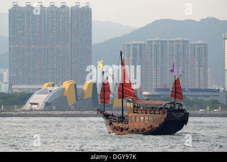 Hong Kong im Abendlicht mit Wolkenkratzern, Turm bauten und einer chinesischen Dschunke mit roten Segeln Kreuzfahrten von der Hong Kong Stockfoto