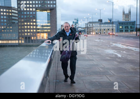 London, UK - 28. Oktober 2013: ein Mann hält auf einem Handlauf beim London Bridge überqueren, als die Stadt von dem Sturm getroffen wird. Der Sturm, genannt St. Jude, brachte das windigste Wetter Großbritannien seit 1987 getroffen. Bildnachweis: Piero Cruciatti/Alamy Live-Nachrichten Stockfoto