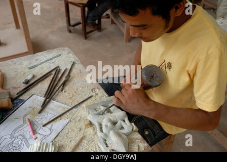 Jungen kambodschanischen Handwerker während des Kunsthandwerks aus Stein mit einem hölzernen Hammer und Meißel, ein traditionelles zu produzieren Stockfoto