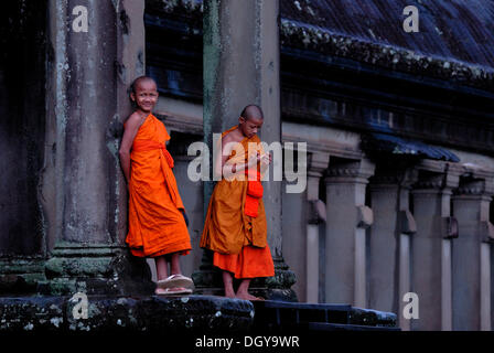 Zwei junge buddhistische Mönche, Novizen tragen orangefarbene Gewänder, die am Eingang des Angkor Wat Tempel Complex, Siem Reap Stockfoto