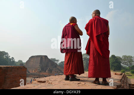 Tibetisch-buddhistische Mönche in roten Gewändern in Meditation und Gebet auf einer Pilgerreise in der archäologischen Stätte der alten Stockfoto