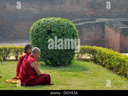 Tibetisch-buddhistische Mönche in roten Gewändern in Meditation und Gebet auf einer Pilgerreise in der archäologischen Stätte der alten Stockfoto