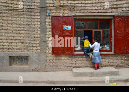 Uigurische muslimische Kinder vor einem grundlegenden Geschäft, Kashgar, Seidenstraße, Xinjiang, China, Volksrepublik China Stockfoto