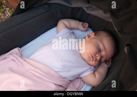 Kleines Mädchen schläft in ihrem Kinderwagen draußen Stockfoto