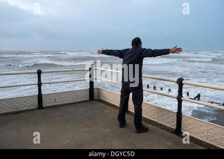 Worthing, UK, 28.10.2013: ein Mann auf Worthing Pier als während der "St. Jude". Der Sturm hatte vor allem durch Tagesanbruch übergeben. Bild von Julie Edwards Stockfoto