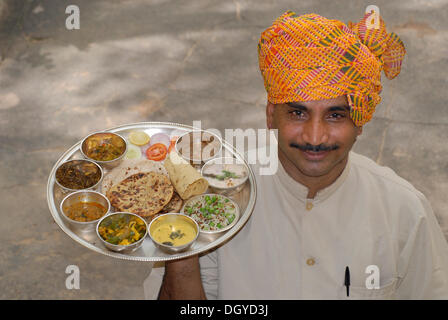 Rajasthani Thali serviert auf einem silbernen Tablett, getragen von Kellner mit Turban, Narain Niwas Heritage Hotel, Jaipur, Rajasthan Stockfoto