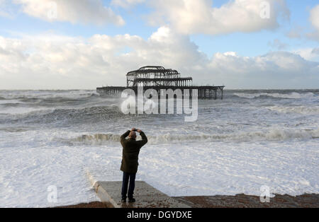 Ein Mann fotografiert der West Pier Brighton wie Stürme die Südküste zerschlagen heute Morgen Sturm, genannt St. Jude, brachte das windigste Wetter Großbritannien seit 1987 getroffen. Stockfoto