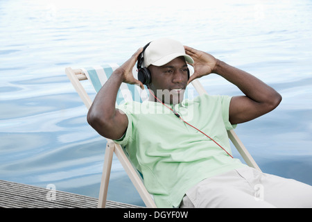 Mann auf Deck Chair von See mit Kopfhörern Stockfoto