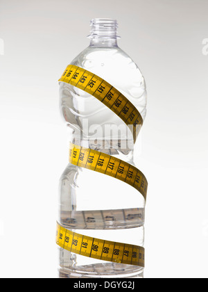 Eine Wasser-Plastikflasche mit Wasser gefüllt und verpackt mit einem Maßband Stockfoto