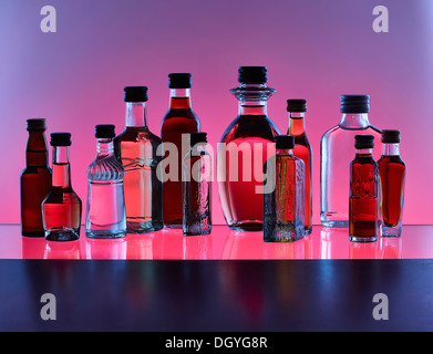 Eine Gruppierung von verschiedenen Miniatur Flaschen Alkohol ohne Etiketten, Gegenlicht, farbigen Hintergrund Stockfoto