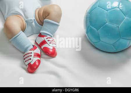 Einen Baby-jungen Baby Fußball Schuhe liegen neben einem Fußball Stockfoto