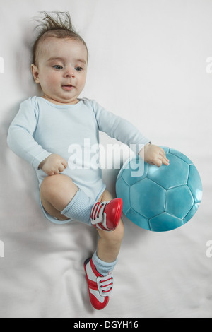 Einen Baby-jungen Baby Fußball Schuhe treten gegen einen Fußball Stockfoto