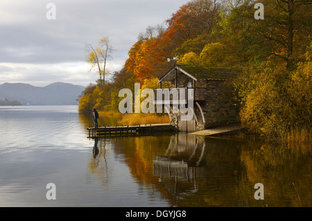 Mann am Steg am Bootshaus Ullswater Herbst Ullswater Lake District National Park Cumbria England United Kingdom. Stockfoto