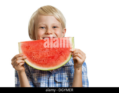 Ein niedlich fröhlicher Junge lächelnd hinter ein saftiges Stück Wassermelone. Isoliert auf weiss. Stockfoto