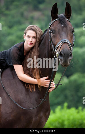 Junge Frau auf einem Pferd sitzen und kuscheln, seinen Hals, Hannoveraner Pferd, Bucht, Nord-Tirol, Austria, Europe Stockfoto
