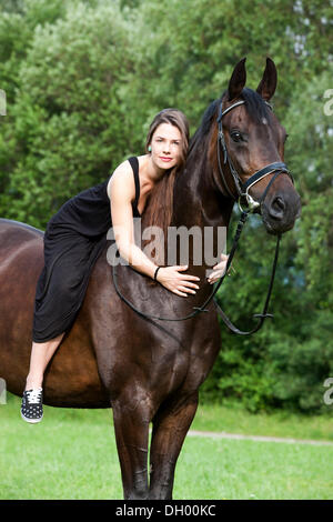 Junge Frau auf einem Pferd sitzen und kuscheln, seinen Hals, Hannoveraner Pferd, Bucht, Nord-Tirol, Austria, Europe Stockfoto
