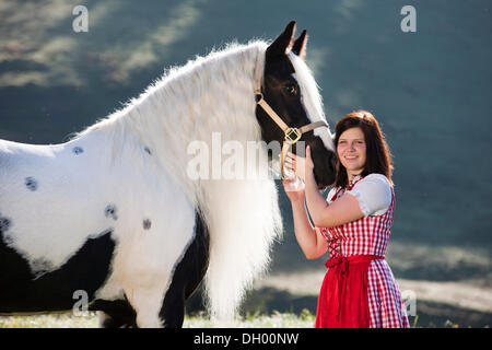 Junge Frau trägt ein Dirndl kuscheln mit einem Gypsy Vanner oder Tinker Pferd, Pinto, schwarz und weiß, Nord-Tirol, Austria, Europe Stockfoto