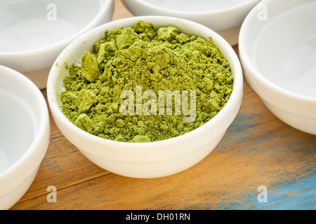 Moringa Blattpulver in einer kleinen Schüssel unter leeren weißen Schalen Stockfoto