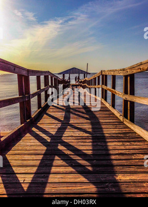 Schatten des Geländers auf hölzerne Dock bei Sonnenuntergang Stockfoto
