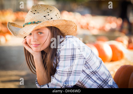 Preteen Mädchen tragen Cowboyhut Porträt im Kürbisbeet in rustikaler Umgebung. Stockfoto