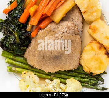 Traditionelle britische Sonntag Mittagessen - Roastbeef, Kartoffeln, Karotten, Pastinaken, Spargel, Grünkohl und Blumenkohl auf einer Platte Stockfoto