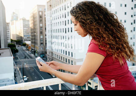 Gemischte Rassen Frau mit Handy auf städtischen Dach Stockfoto