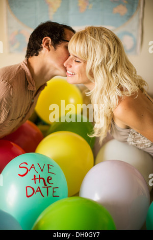 Kaukasische paar küssen über Ballon mit "save the Date" Text Stockfoto