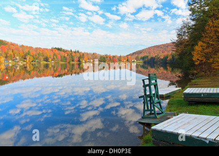 Ein Rettungsschwimmer Stuhl sitzt auf dem Rand der Barsch See in den Catskill Mountains mit einem reflektierten Himmel im Herbst in New York Stockfoto