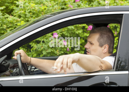 Fahrer mit einer Zigarette in der Hand im Auto Stockfoto