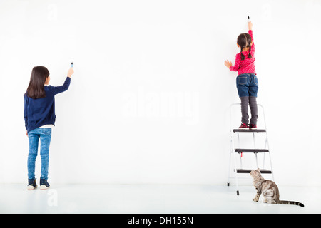 zwei Kinder, die Zeichnung auf die leere weiße Wand Stockfoto