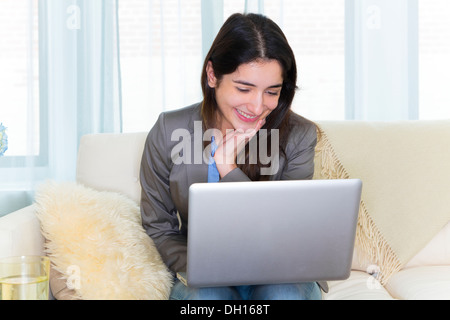 Hispanic Frau mit Laptop auf sofa Stockfoto