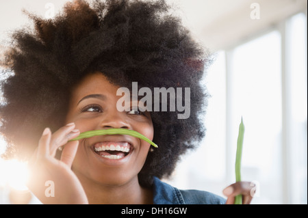 Gemischte Rassen Frau spielt mit grünen Bohnen Stockfoto