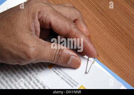 Junger Mann putting Büroklammer auf weißem Papier mit seinem Finger Nahaufnahme von Hand Büroklammer und Papier Herr #743AD Stockfoto