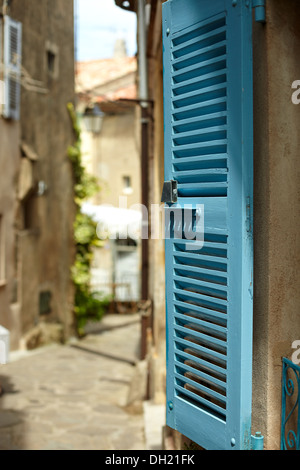 Nahaufnahme eines blau gestrichenen Fensterladens mit leerer Straße in der Ferne, Ramatuelle, Frankreich. Stockfoto