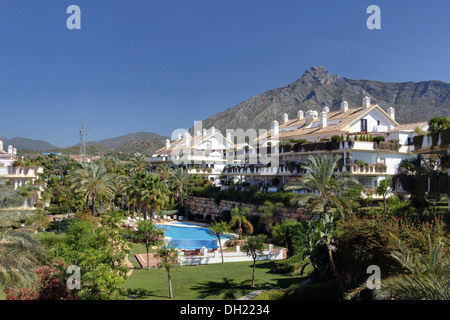 Palmen und Pool im üppig grünen Gärten des gehobenen Ferienwohnungen mit Blick auf die Berge im Süden Spaniens Stockfoto